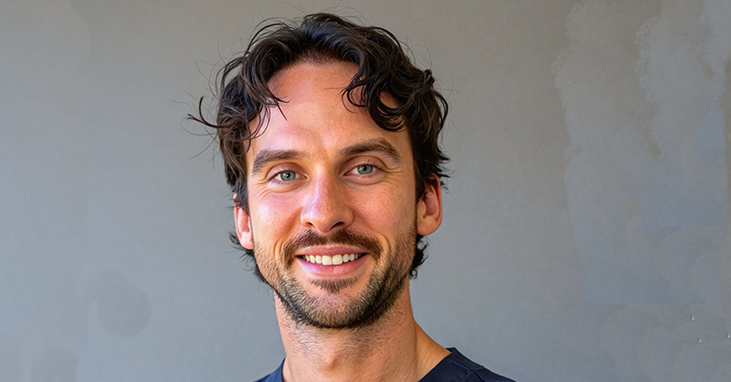 Dr Tom Andrew with curly dark hair wearing a shirt and tie